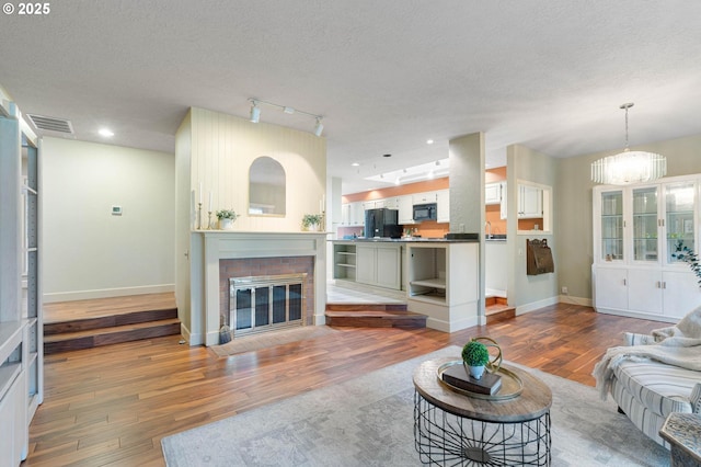 living area with baseboards, visible vents, a chandelier, hardwood / wood-style floors, and a fireplace