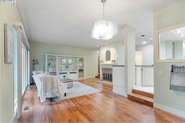 living room with a chandelier, a fireplace, and light hardwood / wood-style flooring