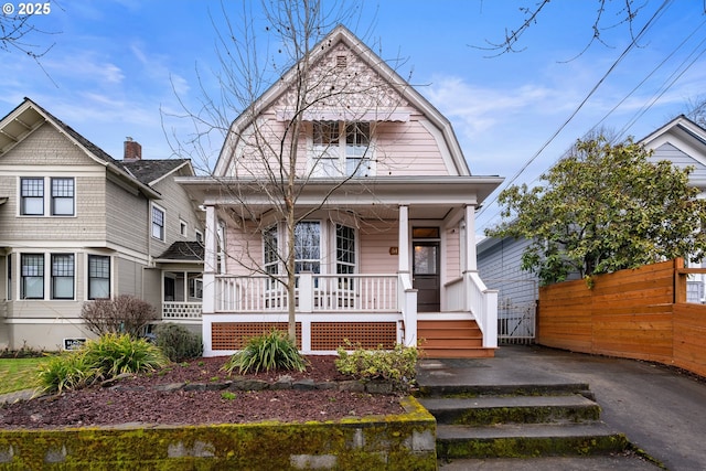 dutch colonial with a gambrel roof, a porch, and fence