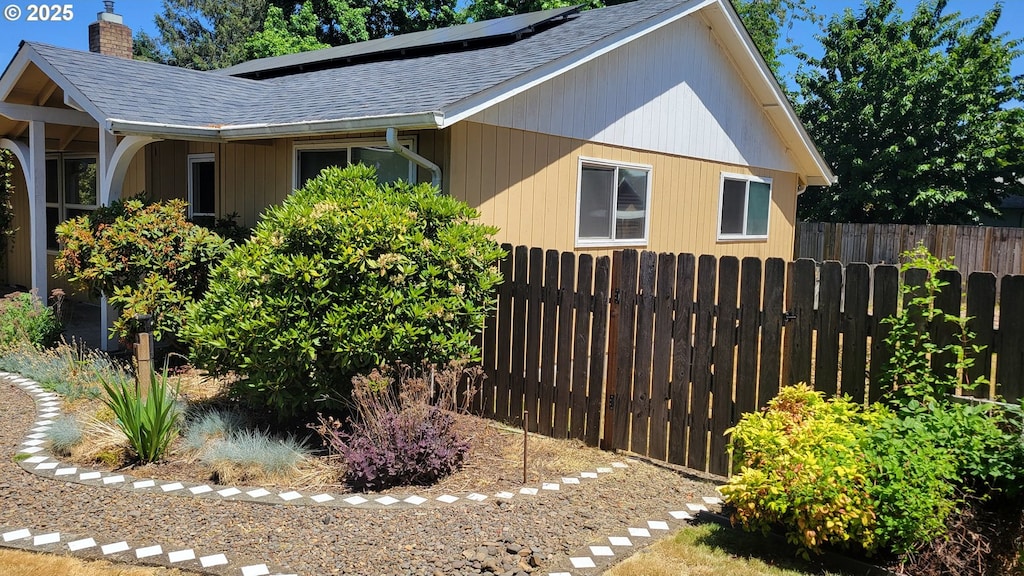 3623 Marion St SE, Albany, OR 97322 - view of property exterior with a shingled roof, a chimney, and roof mounted solar panels