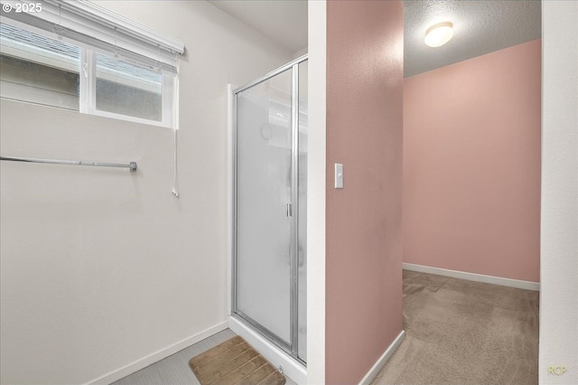 bathroom featuring a textured ceiling, a shower stall, and baseboards