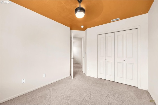 unfurnished bedroom featuring baseboards, visible vents, ceiling fan, carpet, and a closet