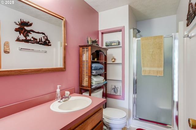 bathroom featuring vanity, a shower with shower door, toilet, and a textured ceiling