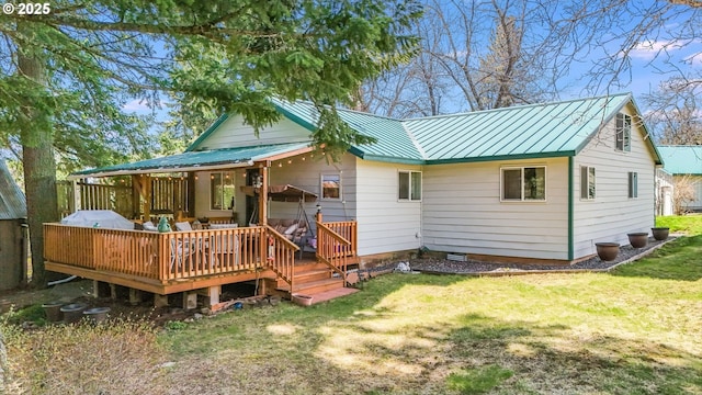 back of property featuring a wooden deck and a lawn