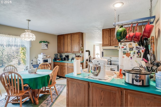 kitchen featuring white appliances, decorative light fixtures, and a textured ceiling