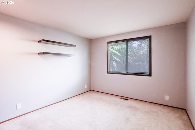 unfurnished room with baseboards, visible vents, and carpet