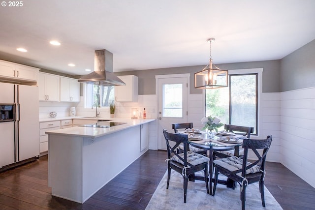 kitchen with a peninsula, island range hood, white fridge with ice dispenser, and dark wood-style floors