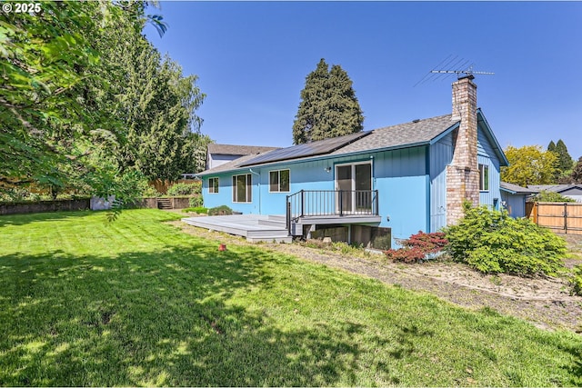 13230 SW Hill Ct, Portland, OR 97223 - back of property featuring roof mounted solar panels, fence, a chimney, a deck, and a yard