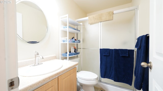 bathroom featuring vanity, toilet, and a shower with shower door