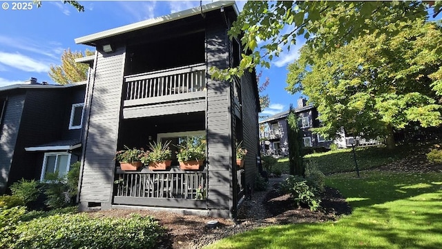 view of side of home featuring a yard and a balcony