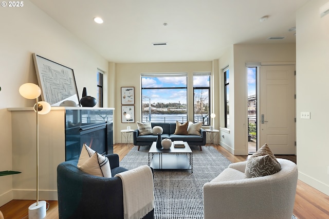 1660 NW Riverscape Dr, Portland, OR 97209 - living room featuring plenty of natural light, a glass covered fireplace, wood finished floors, and recessed lighting