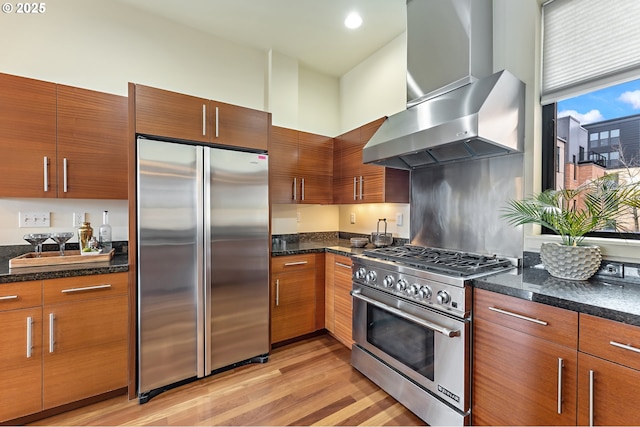 1660 NW Riverscape Dr, Portland, OR 97209 - kitchen with premium appliances, wall chimney range hood, light wood finished floors, and dark stone countertops