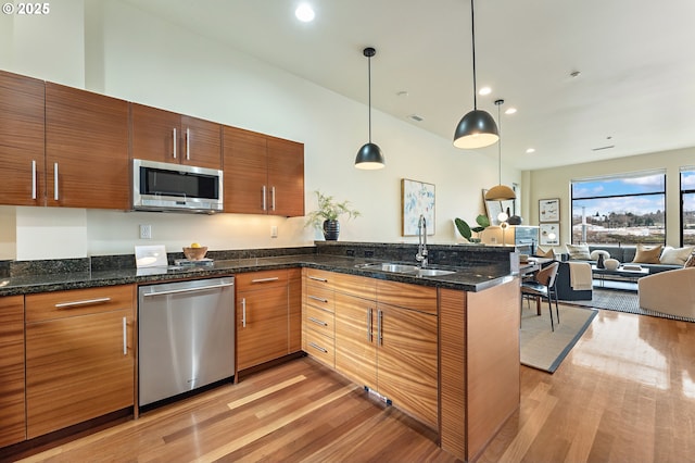 1660 NW Riverscape Dr, Portland, OR 97209 - kitchen featuring stainless steel appliances, a peninsula, light wood-type flooring, open floor plan, and decorative light fixtures