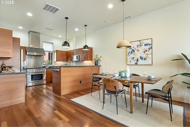 1660 NW Riverscape Dr, Portland, OR 97209 - kitchen with appliances with stainless steel finishes, wall chimney exhaust hood, modern cabinets, dark wood-style floors, and recessed lighting
