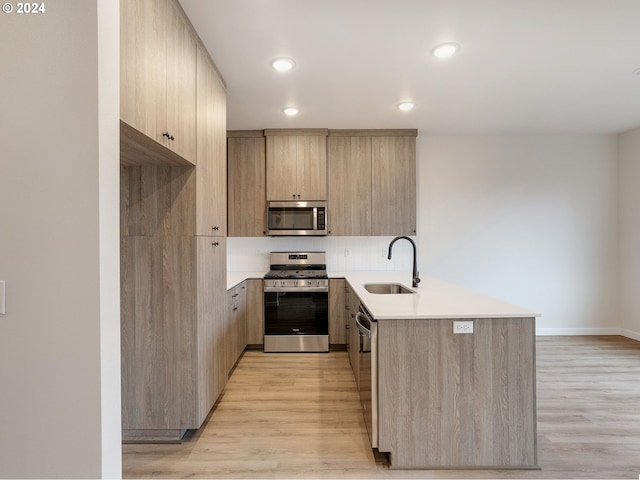 kitchen with sink, light brown cabinets, stainless steel appliances, and light wood-type flooring