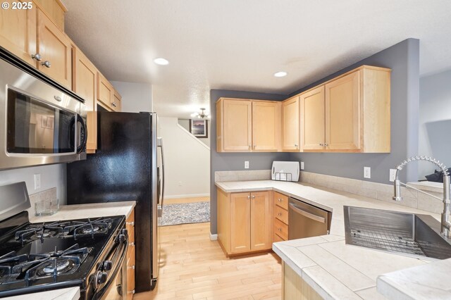 kitchen with light brown cabinetry, sink, stainless steel appliances, and light wood-type flooring