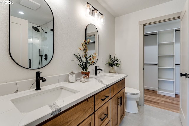 2110 Labona Dr, Eugene, OR 97404 - bathroom featuring a shower with shower door, double vanity, a walk in closet, and tile patterned flooring