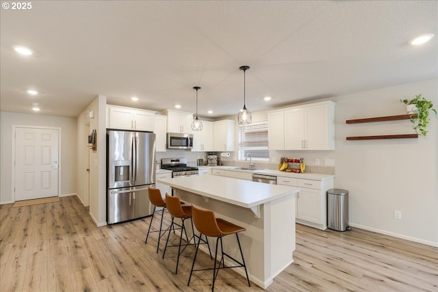 456 Cornwell St, Woodburn, OR 97071 - kitchen with stainless steel appliances, light wood-style floors, a kitchen bar, white cabinets, and recessed lighting