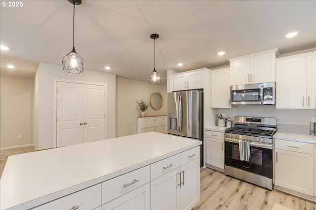 456 Cornwell St, Woodburn, OR 97071 - kitchen featuring stainless steel appliances, light countertops, light wood-style flooring, decorative light fixtures, and white cabinetry