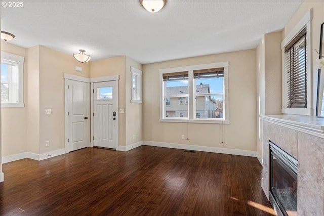 entrance foyer with a tile fireplace and dark wood-type flooring