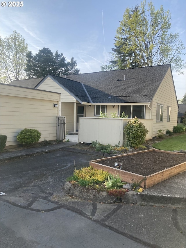 single story home featuring roof with shingles and a vegetable garden