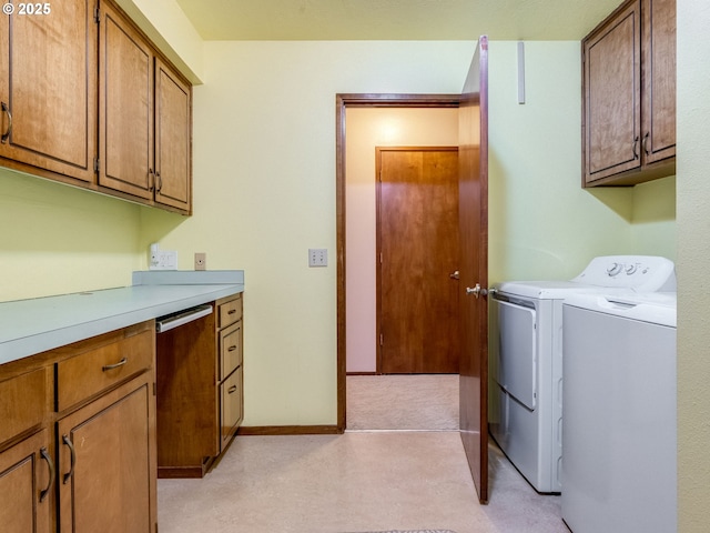 washroom with washing machine and dryer, cabinet space, and baseboards