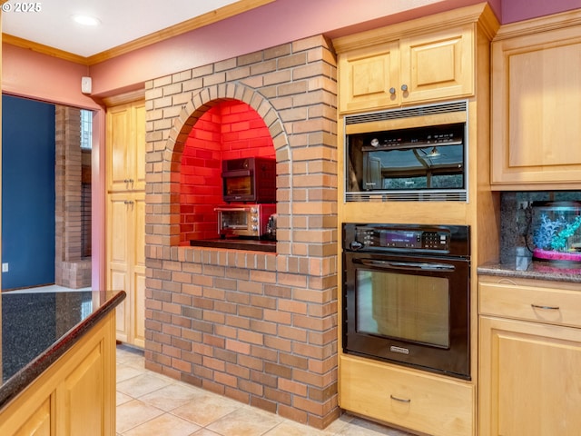 kitchen featuring light tile patterned floors, black oven, dark stone counters, light brown cabinetry, and crown molding