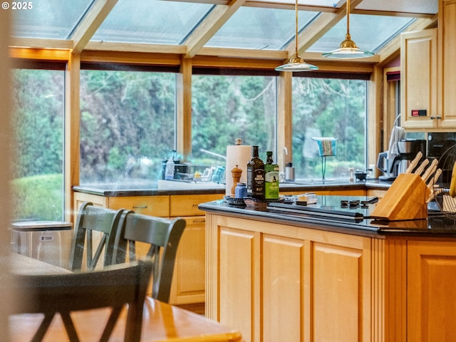 kitchen with dark countertops, light brown cabinets, hanging light fixtures, and gas stovetop