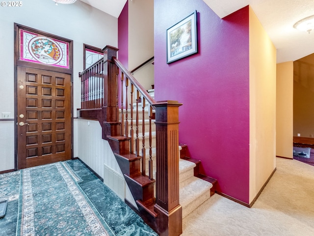 carpeted foyer entrance featuring a high ceiling