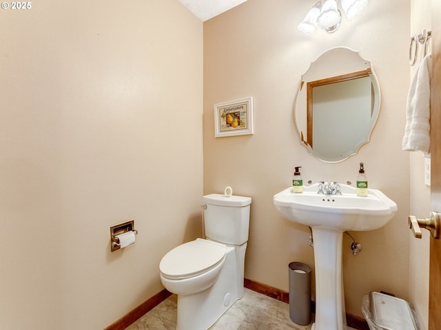 half bathroom featuring baseboards, a sink, and toilet