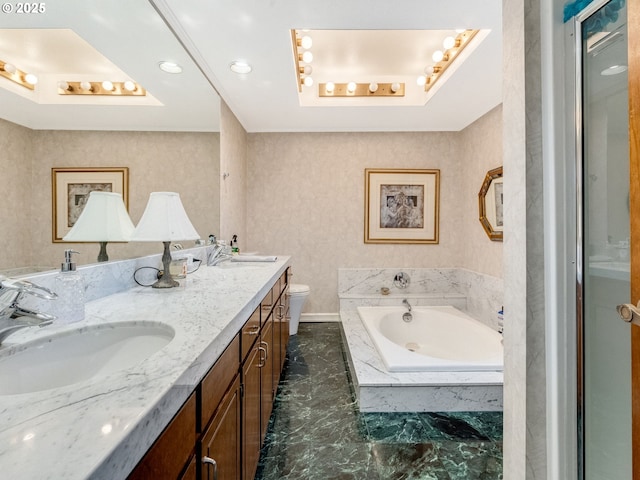 full bathroom with double vanity, toilet, a garden tub, a tray ceiling, and a sink