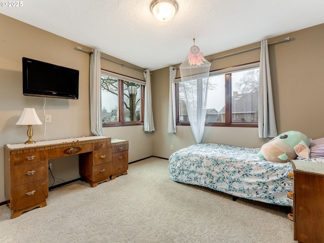 bedroom featuring light colored carpet, a textured ceiling, and baseboards