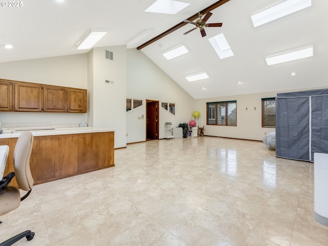 kitchen with high vaulted ceiling, a skylight, beam ceiling, and ceiling fan