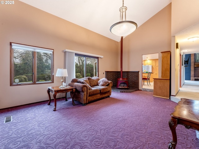 carpeted living room with a wood stove and high vaulted ceiling