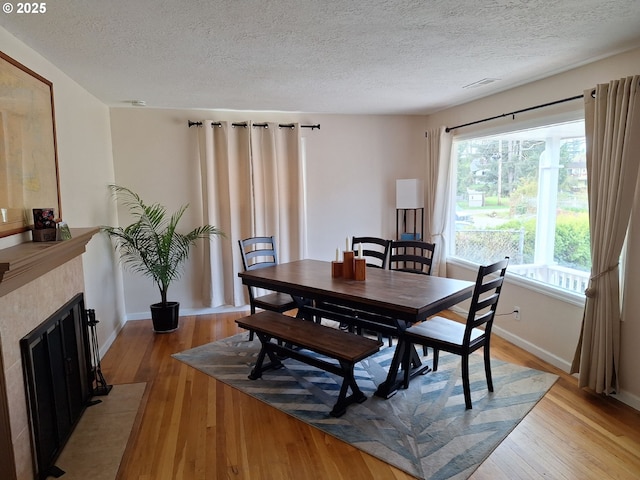 4777 Exeter St, West Linn, OR 97068 - dining area featuring light wood finished floors, a textured ceiling, a fireplace with flush hearth, and baseboards