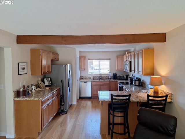 4777 Exeter St, West Linn, OR 97068 - kitchen featuring stainless steel appliances, a sink, a peninsula, light stone counters, and beamed ceiling
