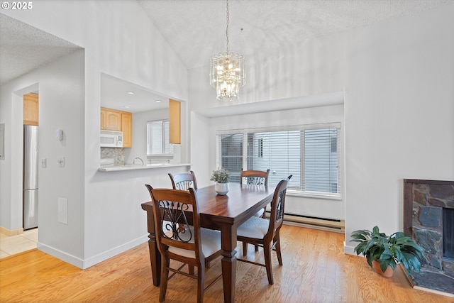 dining area featuring a chandelier, lofted ceiling, light wood-style flooring, and baseboards