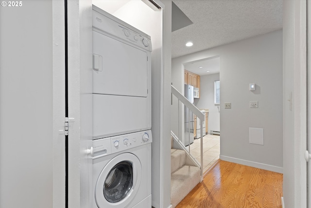 washroom with a textured ceiling, recessed lighting, stacked washer / dryer, baseboards, and light wood-type flooring