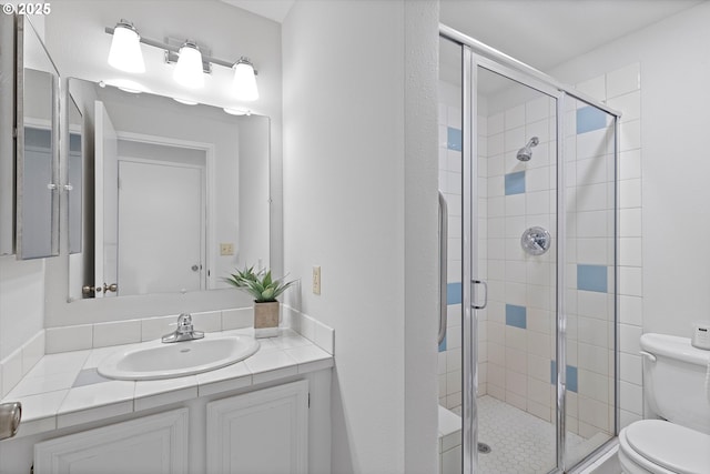 bathroom featuring toilet, a stall shower, and vanity