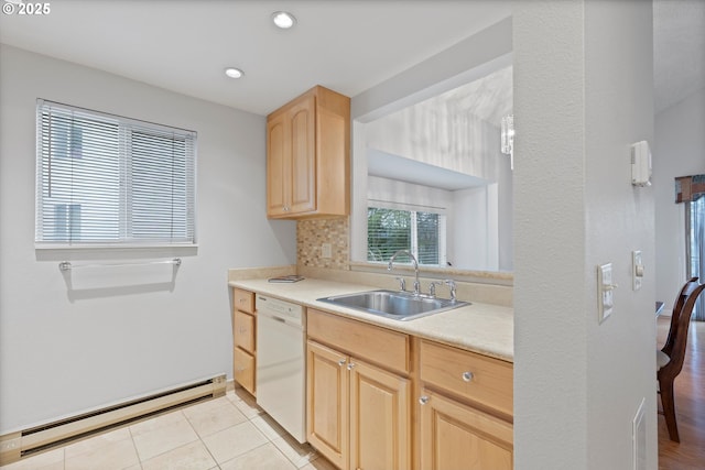 kitchen with a sink, light countertops, baseboard heating, dishwasher, and light brown cabinetry