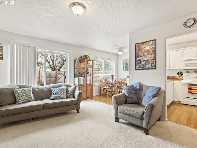 living room featuring ceiling fan, a textured ceiling, and light colored carpet