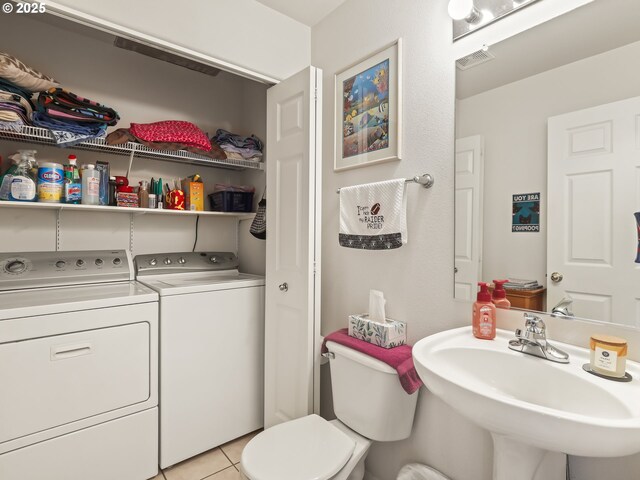 bathroom with tile patterned flooring, washer and clothes dryer, visible vents, toilet, and a sink