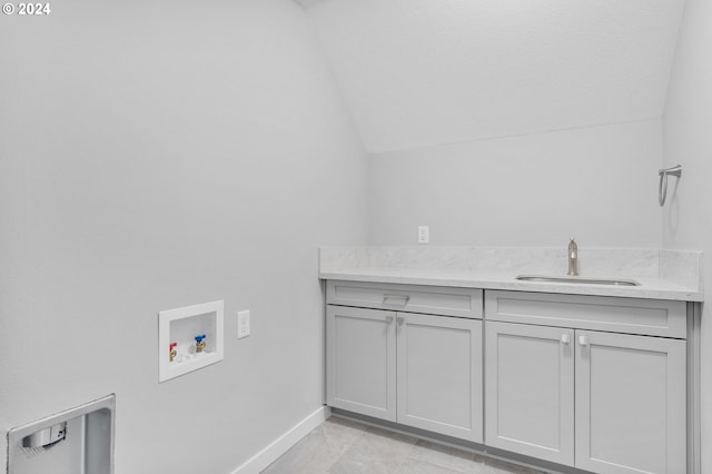 clothes washing area with hookup for a washing machine, sink, and cabinets