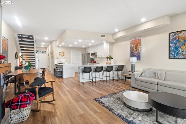 living room with sink and light wood-type flooring