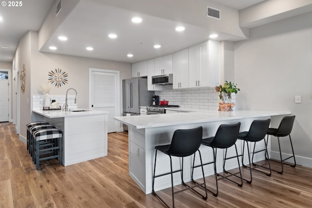 kitchen with high quality appliances, a kitchen breakfast bar, and kitchen peninsula