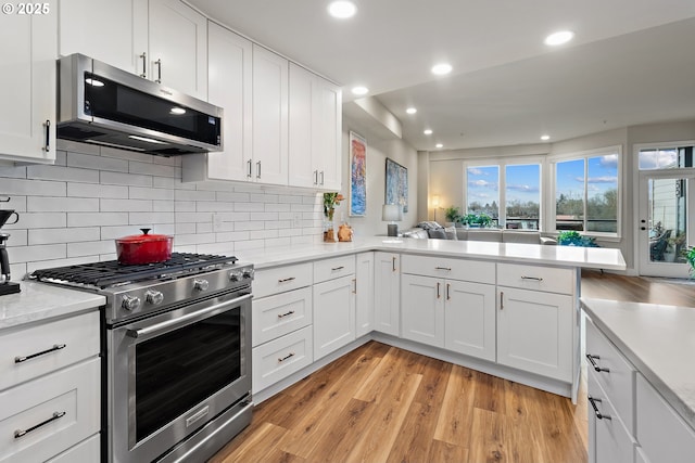 kitchen featuring white cabinetry, light hardwood / wood-style floors, stainless steel appliances, and kitchen peninsula