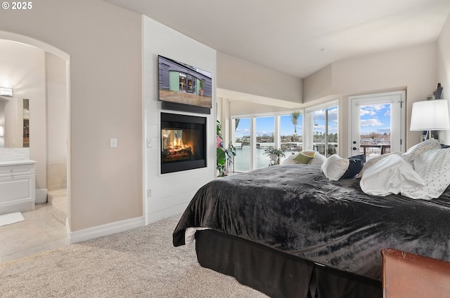 bedroom with light carpet, access to exterior, and a water view