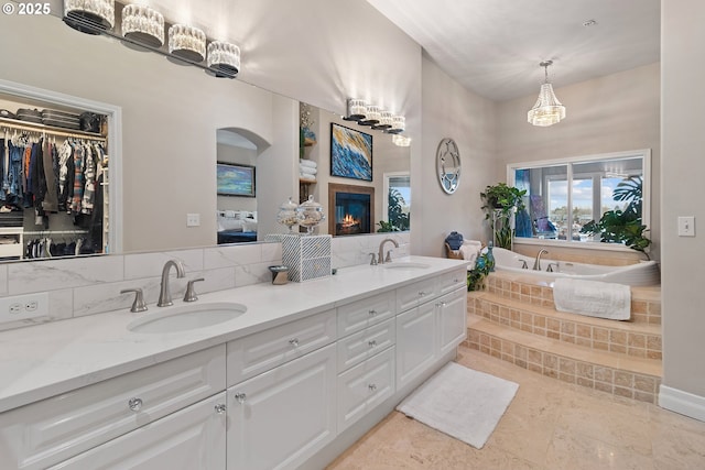 bathroom featuring vanity, a relaxing tiled tub, and decorative backsplash