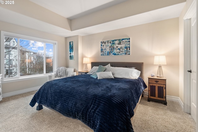 bedroom with light colored carpet and a tray ceiling