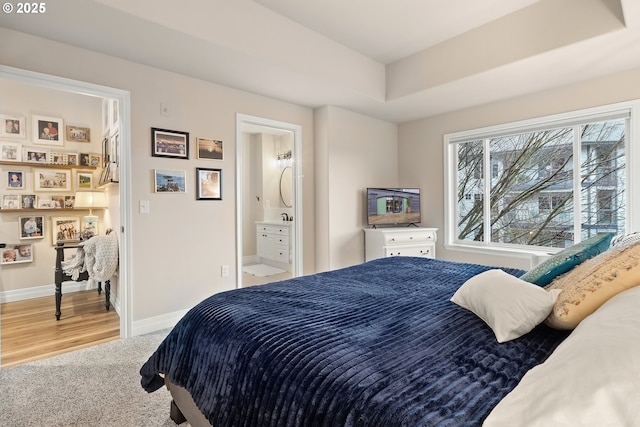 bedroom featuring ensuite bath, a tray ceiling, and carpet floors